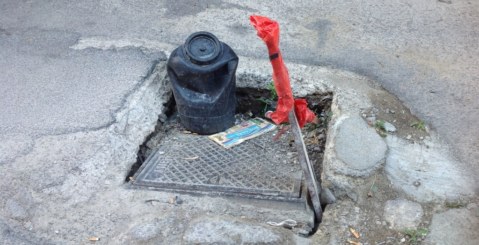 Due tombini semi sprofondati, bisogna intervenire